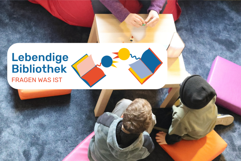 Eine Aufnahme von oben. Zwei Kinder sitzen an einem Tisch. Ihnen gegenüber eine weitere Person. Sie sind im Gespräch miteinander. Dabei sitzen sie auf Kissen auf einem Flauschteppich.
