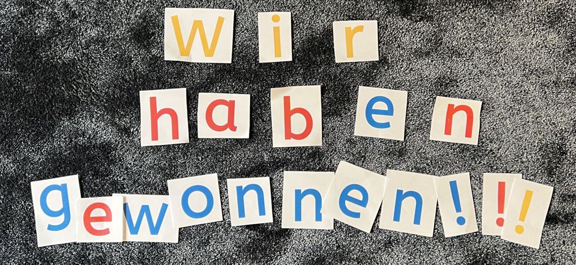 Auf dem Teppich liegen bunte Buchstaben: Wir haben Gewonnen!!!