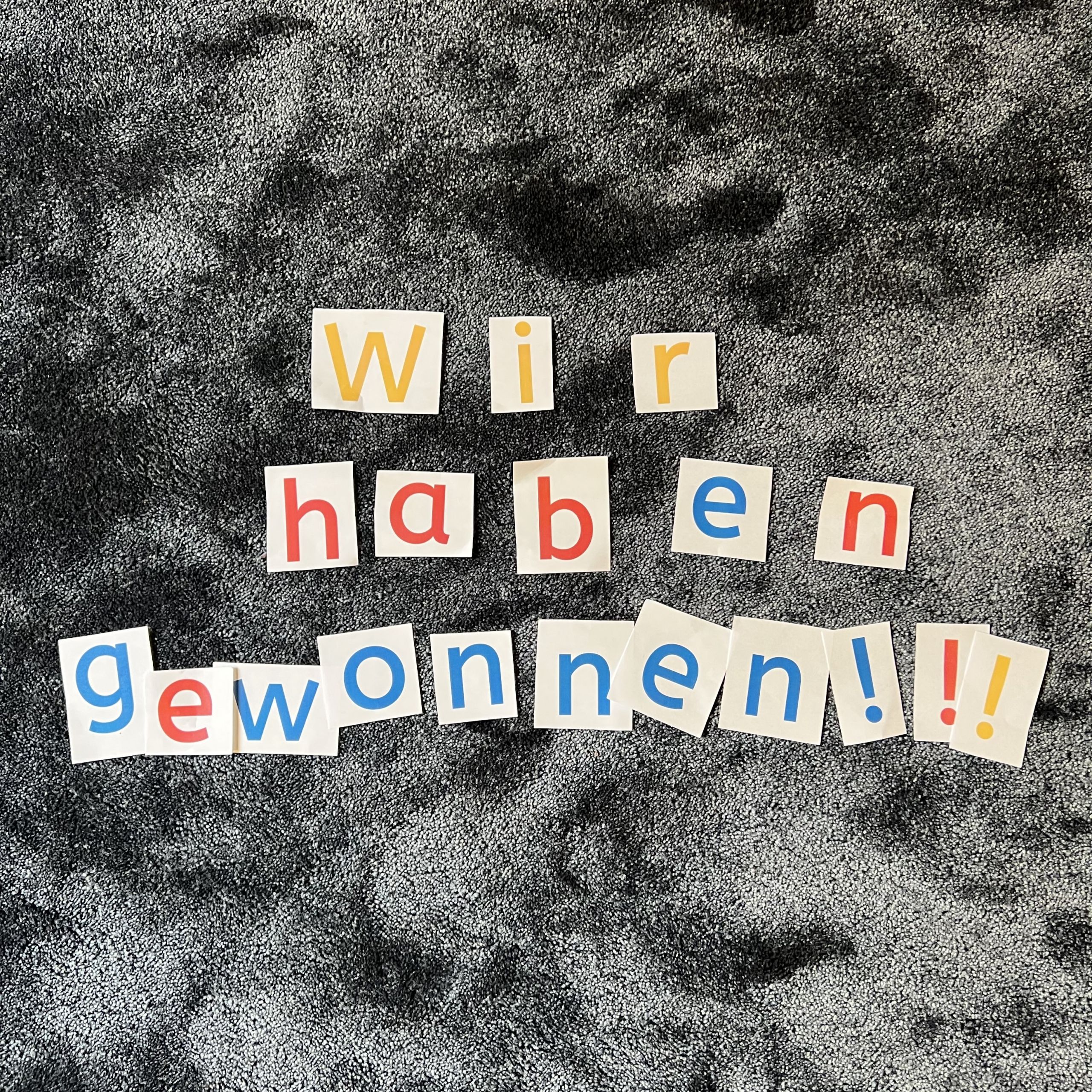 Auf dem Teppich liegen bunte Buchstaben: Wir haben Gewonnen!!!