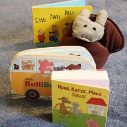 Drei Pappbilderbücher und eine Plüschschnecke