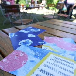 Bunte Postkarten liegen auf einem Tisch im Garten.